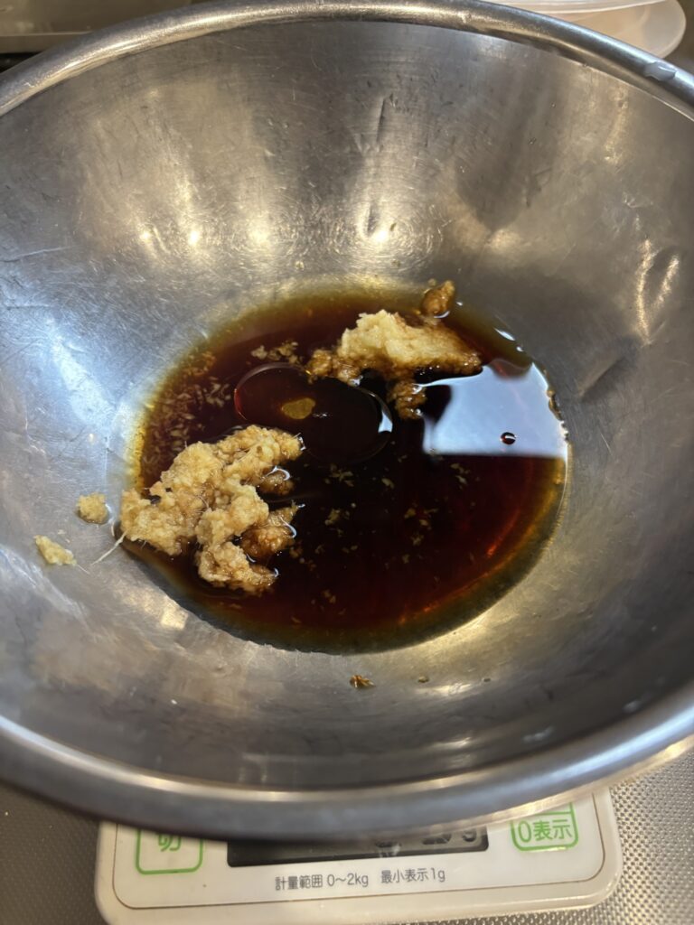 To grate the garlic and ginger. Put the grated mixture into a bowl. Add the soy sauce, cooking sake, and sesame oil.